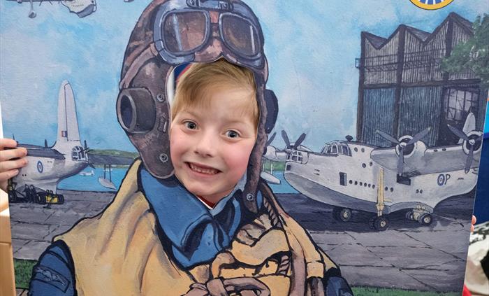 A small boy having his photo taken as a WWII flyiong boat airman